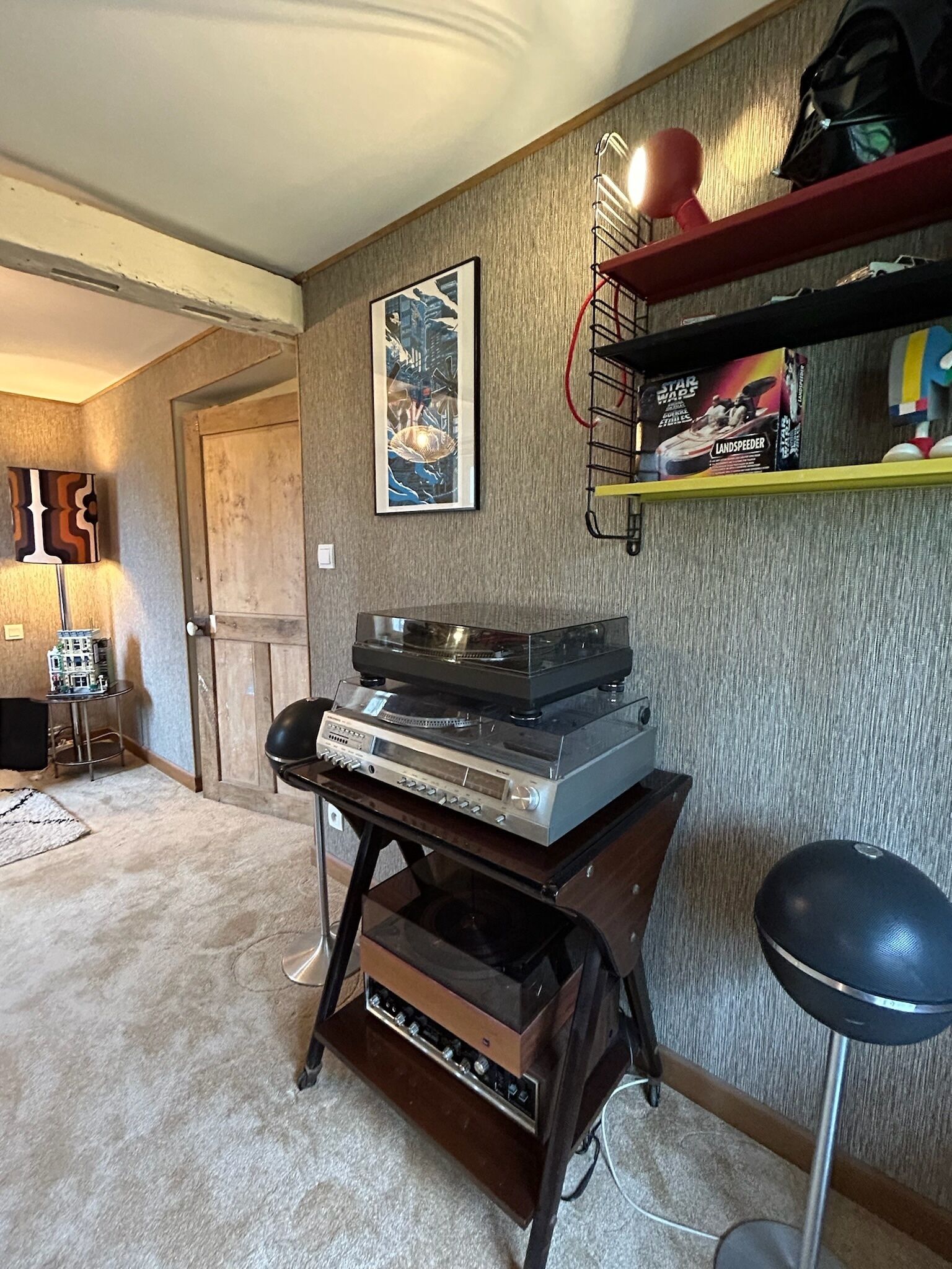 A living room with a vinyl record player, a Star Wars box, and a Star Wars helmet on a shelf.