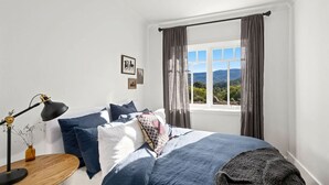 Une chambre à coucher avec un lit, un bureau avec une lampe et une fenêtre avec des rideaux.