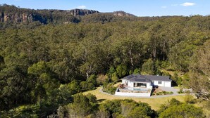 Une maison entourée d’une forêt dense, offrant une vue dégagée sur les montagnes environnantes.