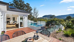 Une maison moderne dotée d’une piscine intérieure à panneaux de verre, d’un espace salon extérieur et offrant une vue panoramique sur les collines.
