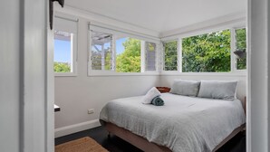 Ein Schlafzimmer mit einem Bett, einem Fenster und Blick auf Grün.