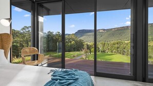 Een slaapkamer met een groot raam met uitzicht op een golfbaan en bergen.