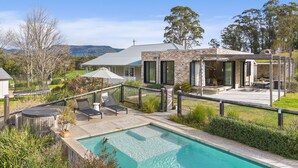 Una casa moderna con piscina, mobiliario exterior y una zona de patio.