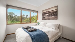 A bedroom with a large window, a bed with white linens, a blue blanket, and a landscape painting on the wall. - Kookaburra Hill, Kangaroo Valley (Kangaroo Valley)