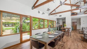 A spacious kitchen with large windows, wooden beams, and a dining area with a table set for four. - Kookaburra Hill, Kangaroo Valley (Kangaroo Valley)