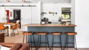 Une cuisine moderne dotée d’un îlot central, de tabourets de bar et d’un coin repas avec une table et des chaises.