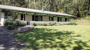 A single-story building with a flat roof, a front porch with a white picket fence, and a well-maintained lawn. - Lavender Hill, Kangaroo Valley (Kangaroo Valley)