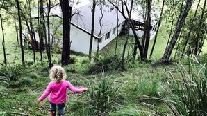 A child in a pink shirt walking through a grassy area with trees and a house in the background. - Lavender Hill, Kangaroo Valley (Kangaroo Valley)
