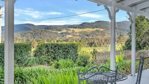 A covered outdoor area with a view of rolling hills and a wooden fence.
