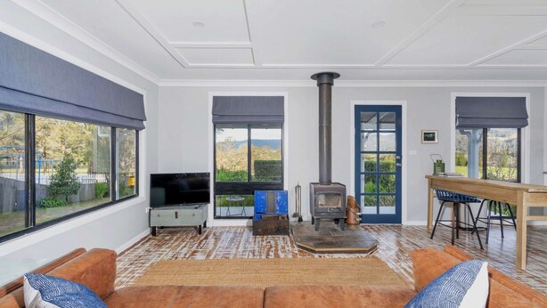 A spacious living room with a large window, a fireplace, a television, and a dining area.