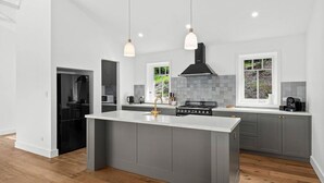 Une cuisine moderne dotée d’un îlot central, de meubles de couleur grise et d’une hotte noire.