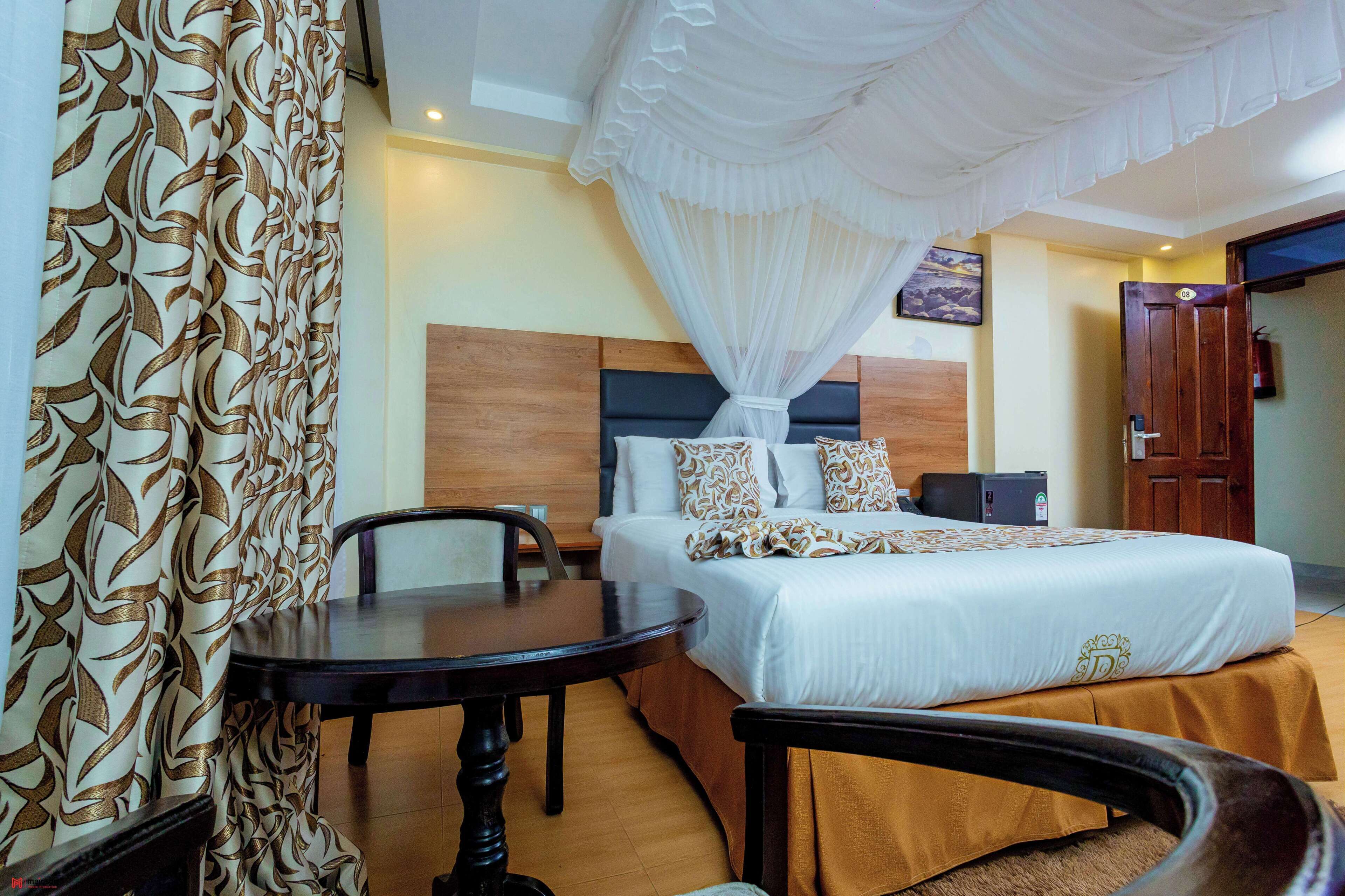 A hotel room with a bed, a bedside table, a chair, a small desk, and a wardrobe.