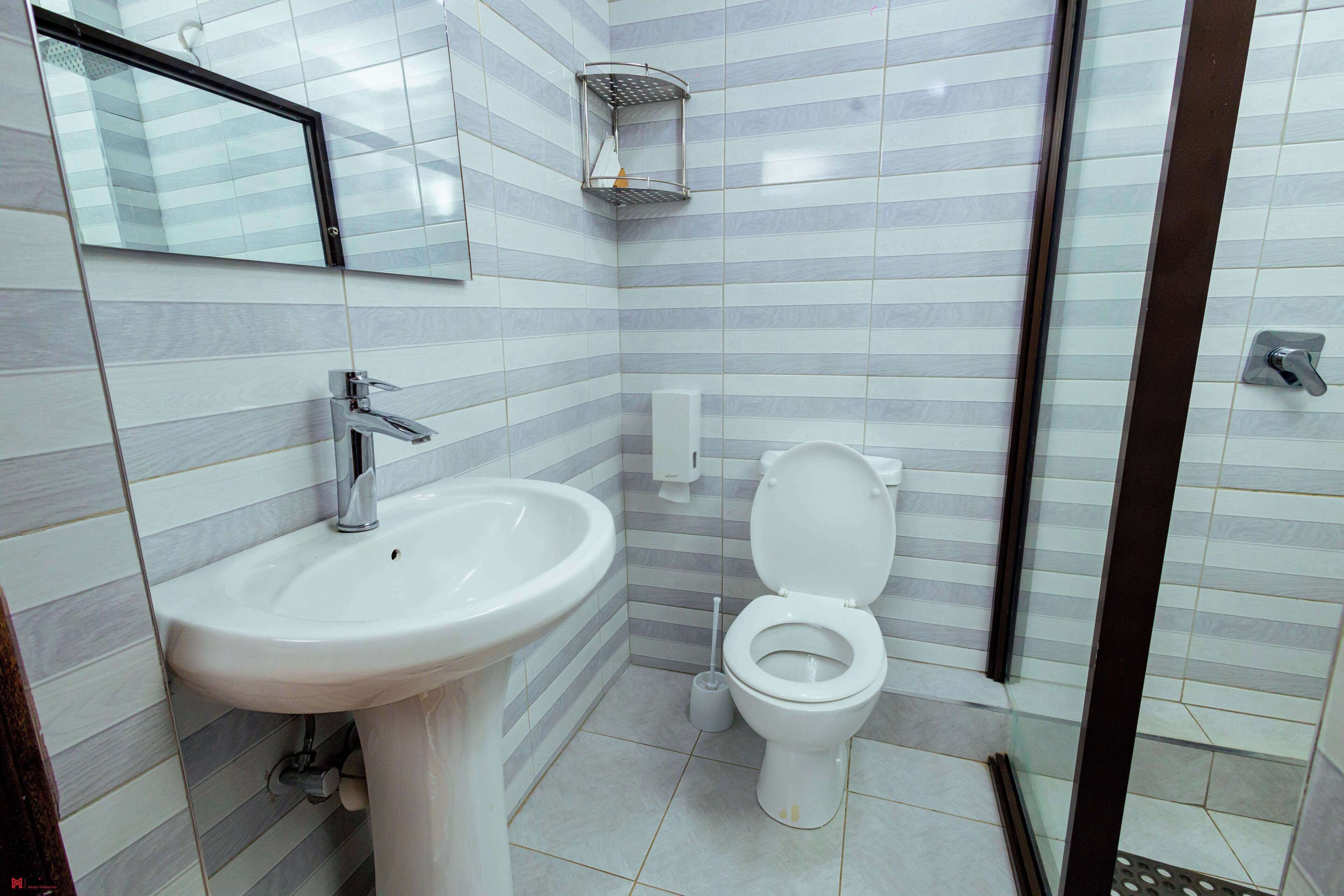 Un baño con lavamanos, inodoro y zona de ducha.