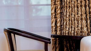A room with a wooden chair, a small table, and patterned curtains.