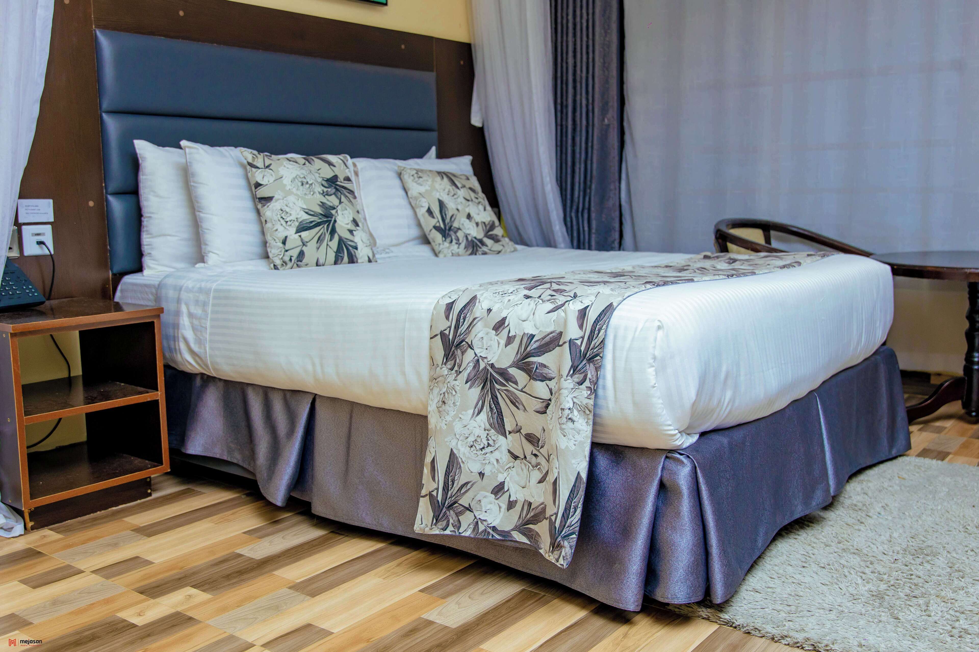 A hotel room with a bed, a nightstand, a desk, and a chair.