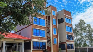 A multi-story building with a red roof, large windows, and a covered entrance with a railing. - Grand Duke Hotel Limited (Homa Bay)