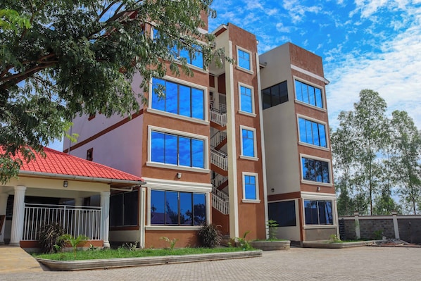Un edificio de varios pisos con techo rojo, ventanas grandes y un acceso cubierto con barandilla.