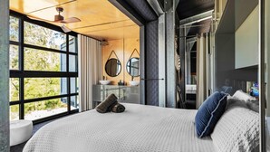 A bedroom with a large window, a bed with pillows, a bedside table, and a mirror. - Sky Ridge, Kangaroo Valley (Kangaroo Valley)