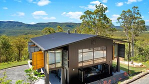A modern house with large windows, a garage, and a patio area. - Sky Ridge, Kangaroo Valley (Kangaroo Valley)
