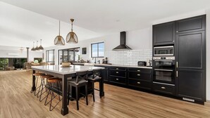 A modern kitchen with a large island, black cabinetry, and stainless steel appliances. - Valley View Estate, Kangaroo Valley (Beaumont, Kangaroo Valley)