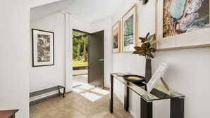 A hallway with framed artwork, a glass console table, and a door leading to an outdoor area. - Valley View Studio, Kangaroo Valley (Beaumont, Kangaroo Valley)