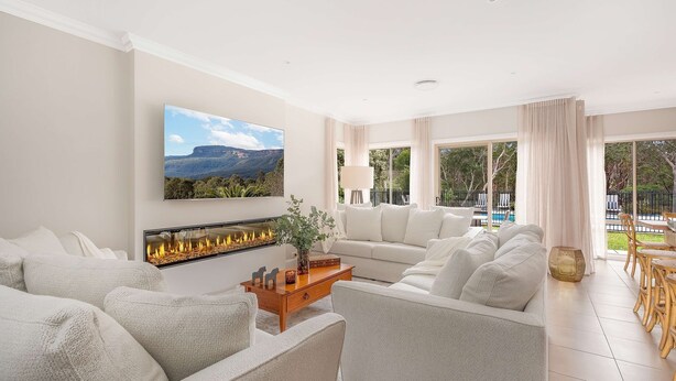 A spacious living room with a fireplace, a large flat-screen TV, and a view of a pool and garden. - Westbrook, Kangaroo Valley (Kangaroo Valley)