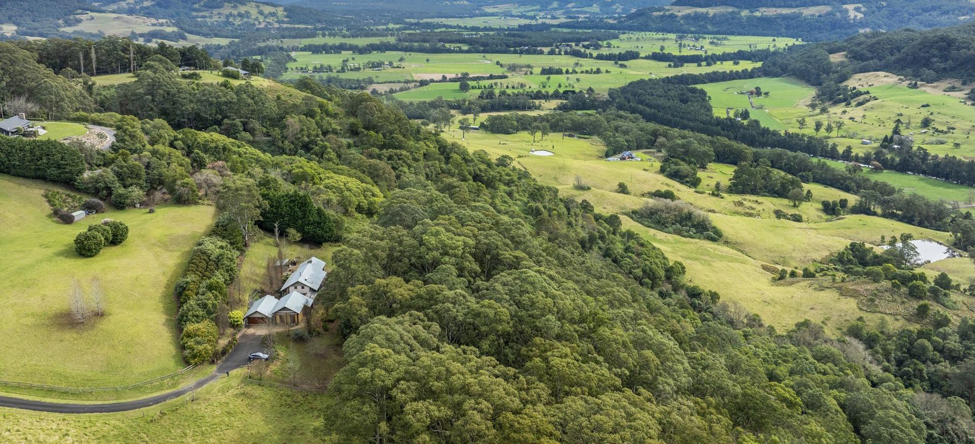 An aerial view of Kangaroo Valley Village, featuring rolling hills, lush greenery, and scattered buildings.