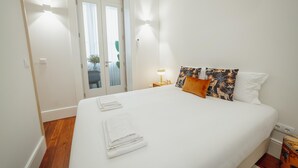 A neatly made bed with white linens, a nightstand with a lamp, and decorative pillows. - Home With A Pool by Vacationy (Porto)