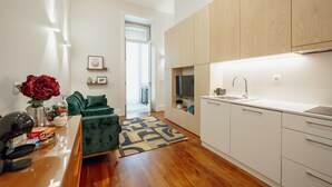 A modern kitchen with white cabinets, a built-in oven, and a sink. There is a green sofa and a coffee table in the living area. - Home With A Pool by Vacationy (Porto)