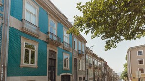 A row of townhouses with balconies, a clear street, and parked cars. - Home With A Pool by Vacationy (Porto)