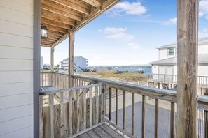 Una terraza de madera con vista a la playa y edificios a lo lejos.