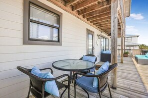 Eine überdachte Terrasse im Freien mit Korbmöbeln und einem Glastisch.