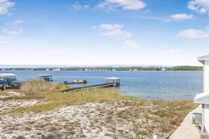 A waterfront property with a sandy beach, dock, and a building adjacent to the water. - Heron Landing 14- Beach access, on Little Lagoon (Gulf Shores)