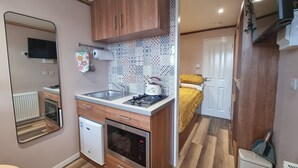 Uma cozinha compacta com armários de madeira, forno embutido, micro-ondas e pia.