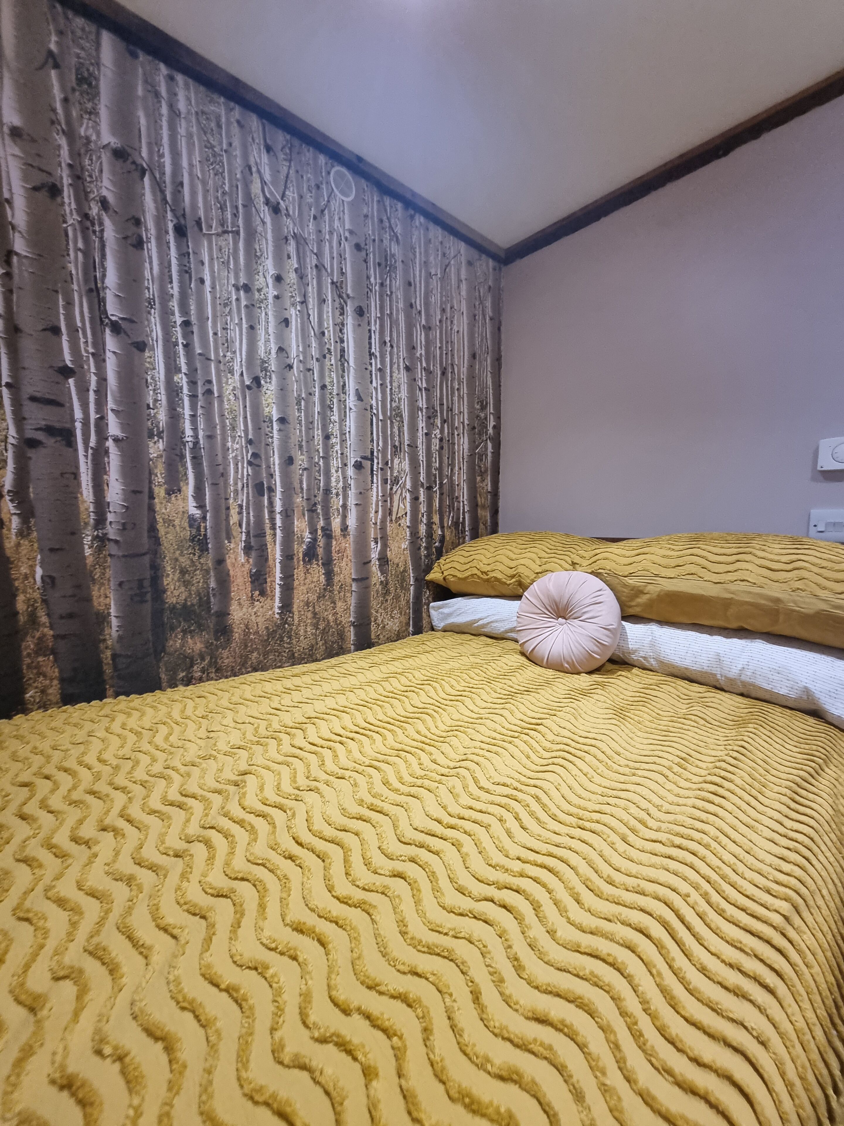 A room with a bed, a textured wall, and a wall-mounted thermostat.