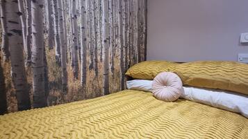 A room with a bed, a textured wall, and a wall-mounted thermostat.