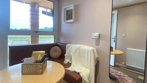Um quarto aconchegante com uma mesa redonda, um banco, um espelho grande e uma janela com vista para o exterior.
