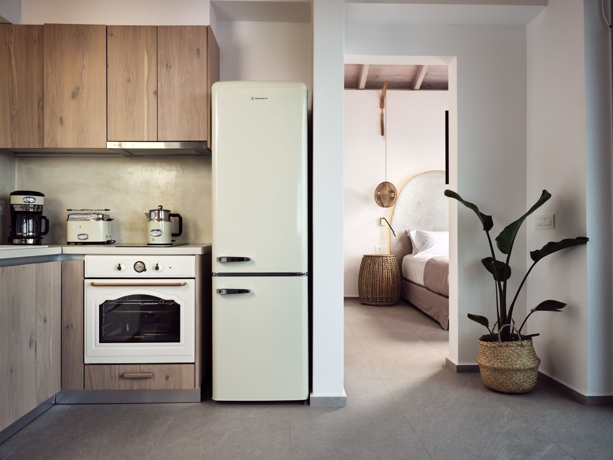 A compact kitchen with a white refrigerator, wooden cabinets, a built-in oven, and a coffee maker.