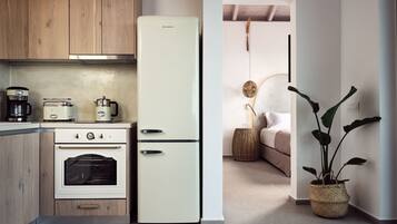 A compact kitchen with a white refrigerator, wooden cabinets, a built-in oven, and a coffee maker.