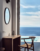 Una habitación con un escritorio de madera, una silla, un espejo grande y vistas al océano.