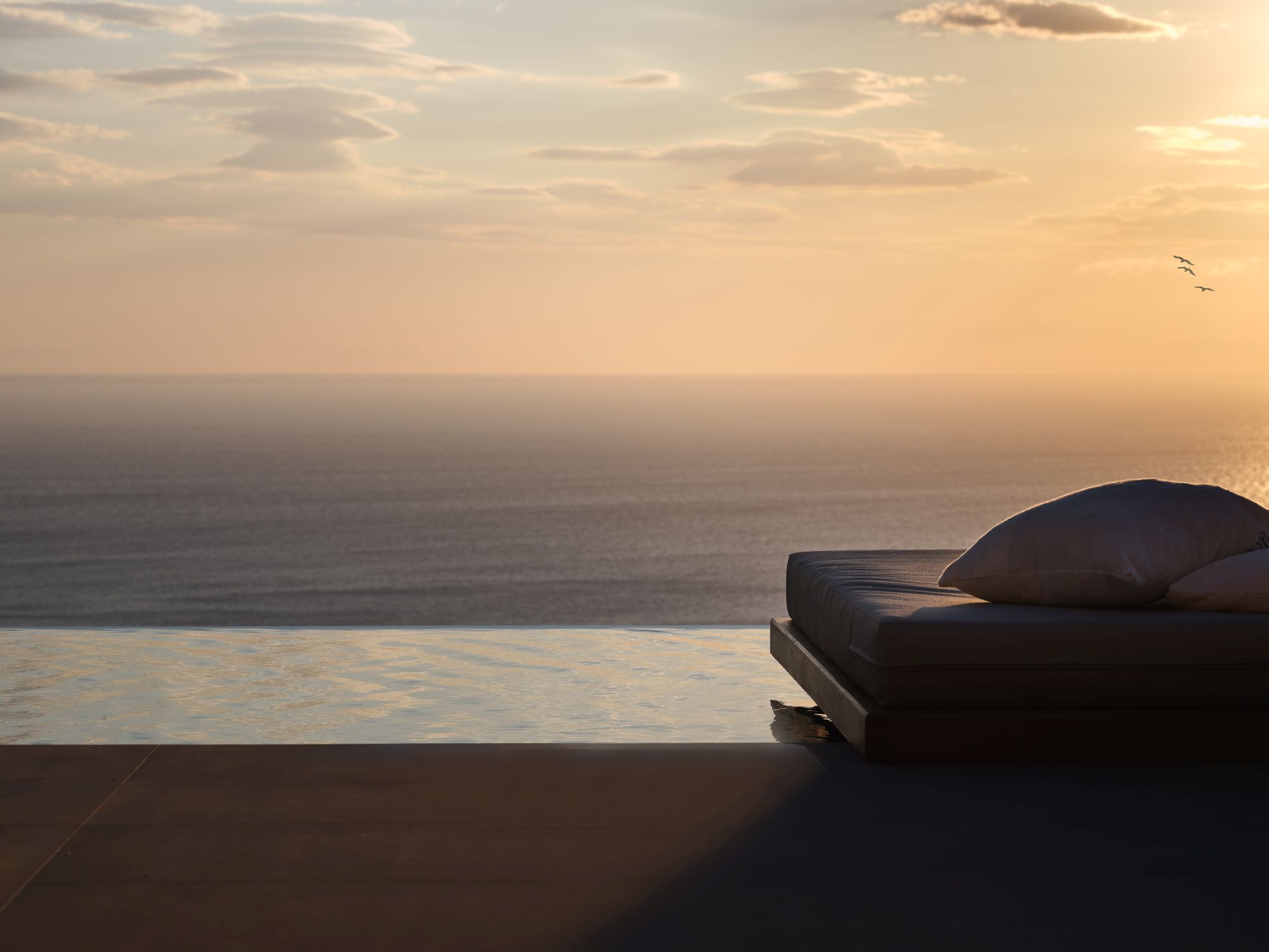 A bedroom with a view of the ocean at sunset.