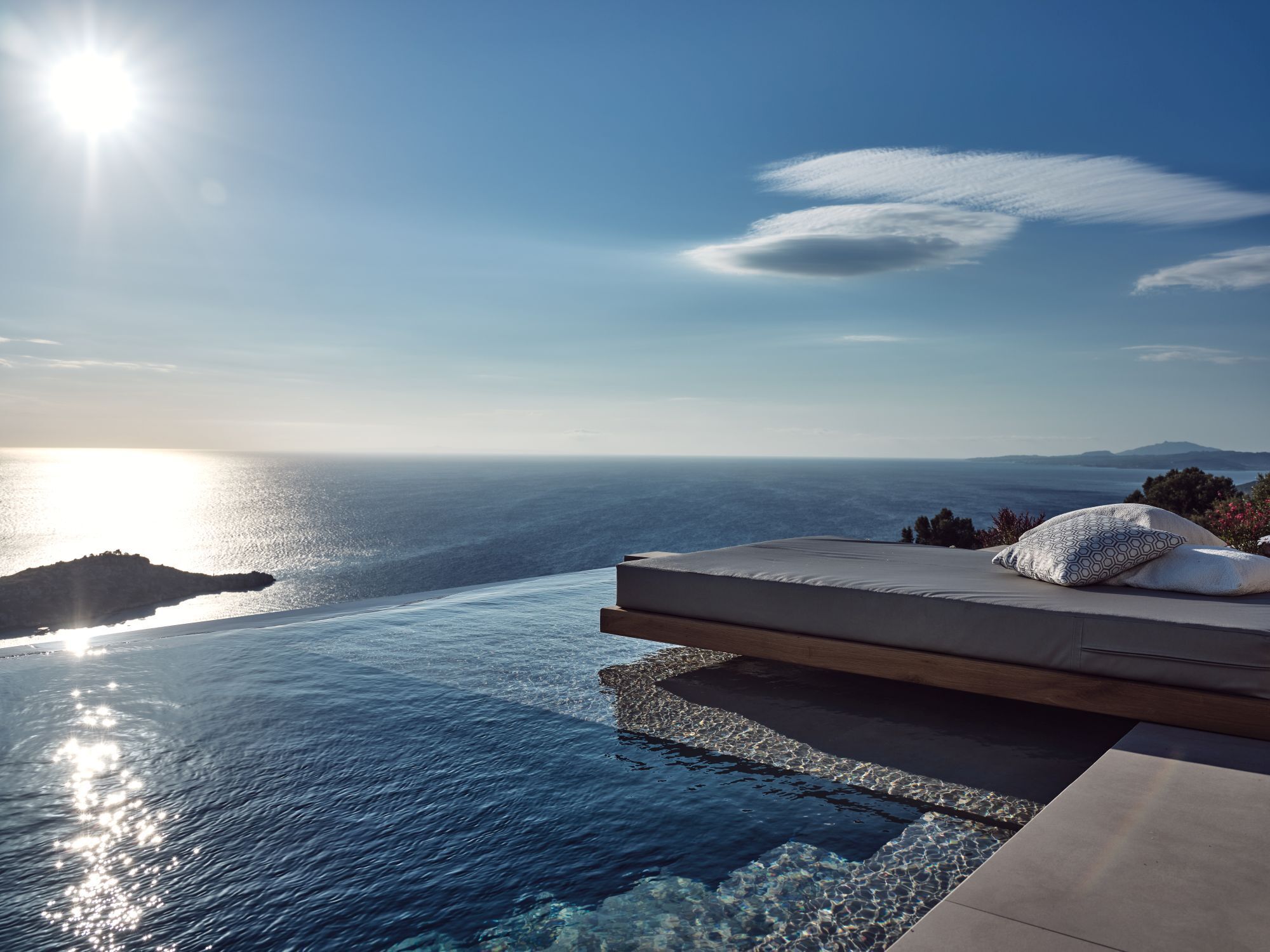 A luxurious outdoor seating area with a view of the sea and distant mountains.