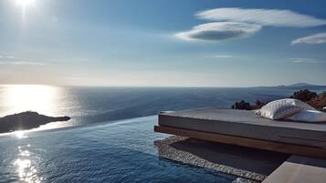 A luxurious outdoor seating area with a view of the sea and distant mountains.