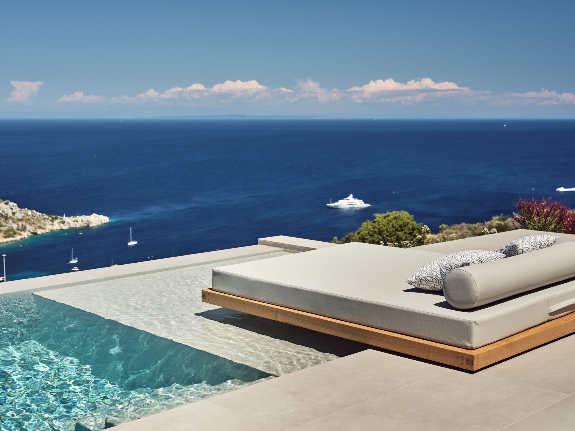 A modern infinity pool with a clear view of the ocean and yachts.