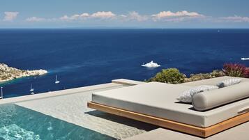 A modern infinity pool with a clear view of the ocean and yachts.