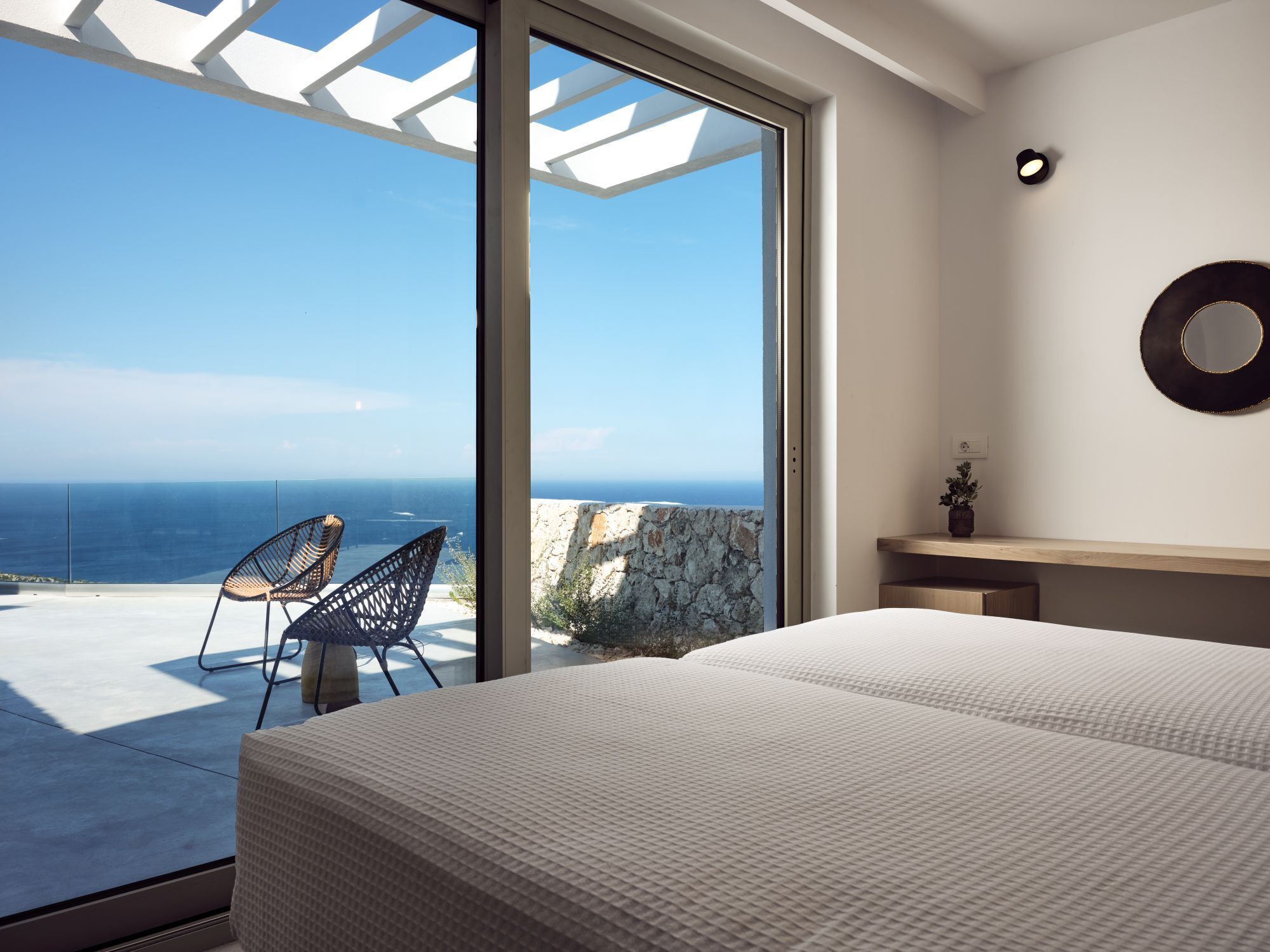 Ein Schlafzimmer mit einem großen Bett, Meerblick und einem Sessel am Fenster.