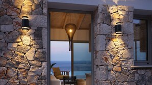 Une entrée en pierre avec un éclairage intégré, une vue sur l’océan et un espace détente avec un canapé et un fauteuil.