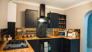 Una cocina moderna con armarios negros, encimera de madera, horno empotrado y microondas.