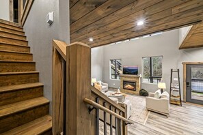 A staircase leading to a living area with a fireplace, a sofa, and a television.
