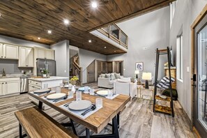 Una cucina moderna con pensili bianchi, un tavolo da pranzo in legno apparecchiato per quattro persone e una scala che conduce a un piano superiore.